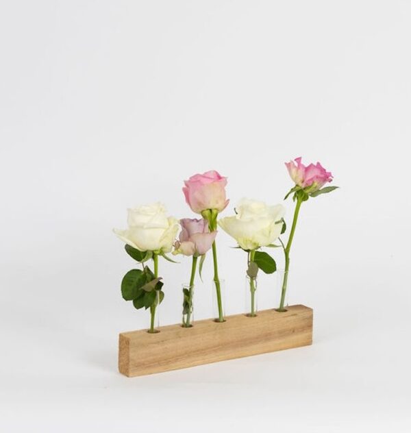 Houten bloemenhouder met glazen buisjes en verse rozen.